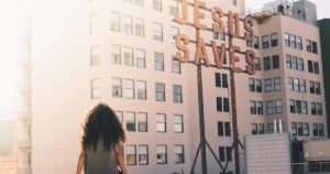 Girl overlooking city with Jesus Saves sign — social sharing image