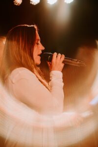 woman holding microphone while singing on stage